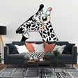 Contemplative giraffe wall sticker with colorful headphones on white wall above modern sofa.