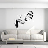 Girl silhouette wall sticker releasing birds above a stylish white sofa in a modern living room.