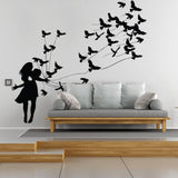 Girl silhouette wall sticker releasing birds above a modern sofa.