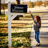 Little girl reaching for a personalized mailbox with custom address decal on a sunny day.