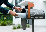 Person inserting mail into a personalized mailbox featuring a custom decal with name and address.