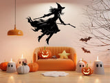 Flying broom figure silhouette wall decal displayed above a sofa.