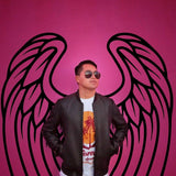 Person in sunglasses standing confidently in front of pink angel wings mural, showcasing urban style and creativity.