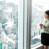 Woman enjoying city view with FeatherGuard bird protection decals on windows to prevent bird strikes.