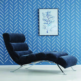 Stylish living room featuring herringbone wall stickers, modern blue chair, and framed art on wall.