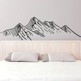 Mountain silhouette wall decal above a bed, adding a touch of nature and adventure to home decor.