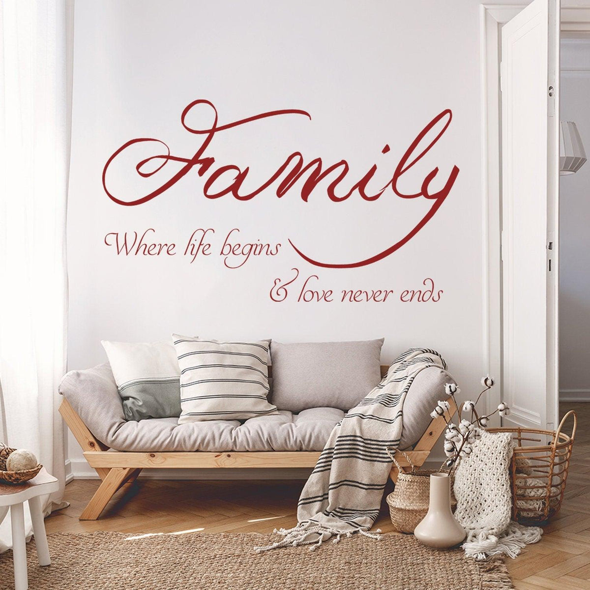 Family quote wall sticker in red script on a white wall above a cozy couch, expressing love and togetherness.