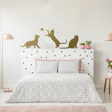 Decorative wall decal of playful cats above a bed with polka dot bedding in a stylish bedroom.