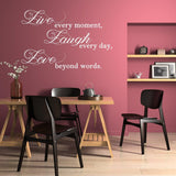 Live Laugh Love wall sticker in a stylish dining area with black chairs and pink walls for a positive decor.