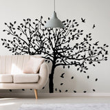 Black birch tree wall decal with birds and leaves in modern living room setting.