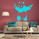 Panda with pistols wall sticker above a beige couch.