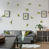 12 flock of birds wall stickers in green vinyl above a living room couch with plants and artwork.