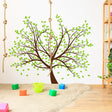 Tree sticker decal featuring brown branches and green leaves on a nursery wall, enhancing the playful decor.
