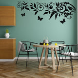Black butterfly vinyl wall decals over a teal kitchen wall with a wooden table and black chairs.