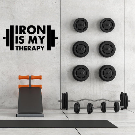 Наклейка Iron Is My Therapy на стене домашнего спортзала рядом с тренажёрами.