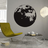 Moon phase wall decor decal in a modern nursery with yellow chair and decorative table.