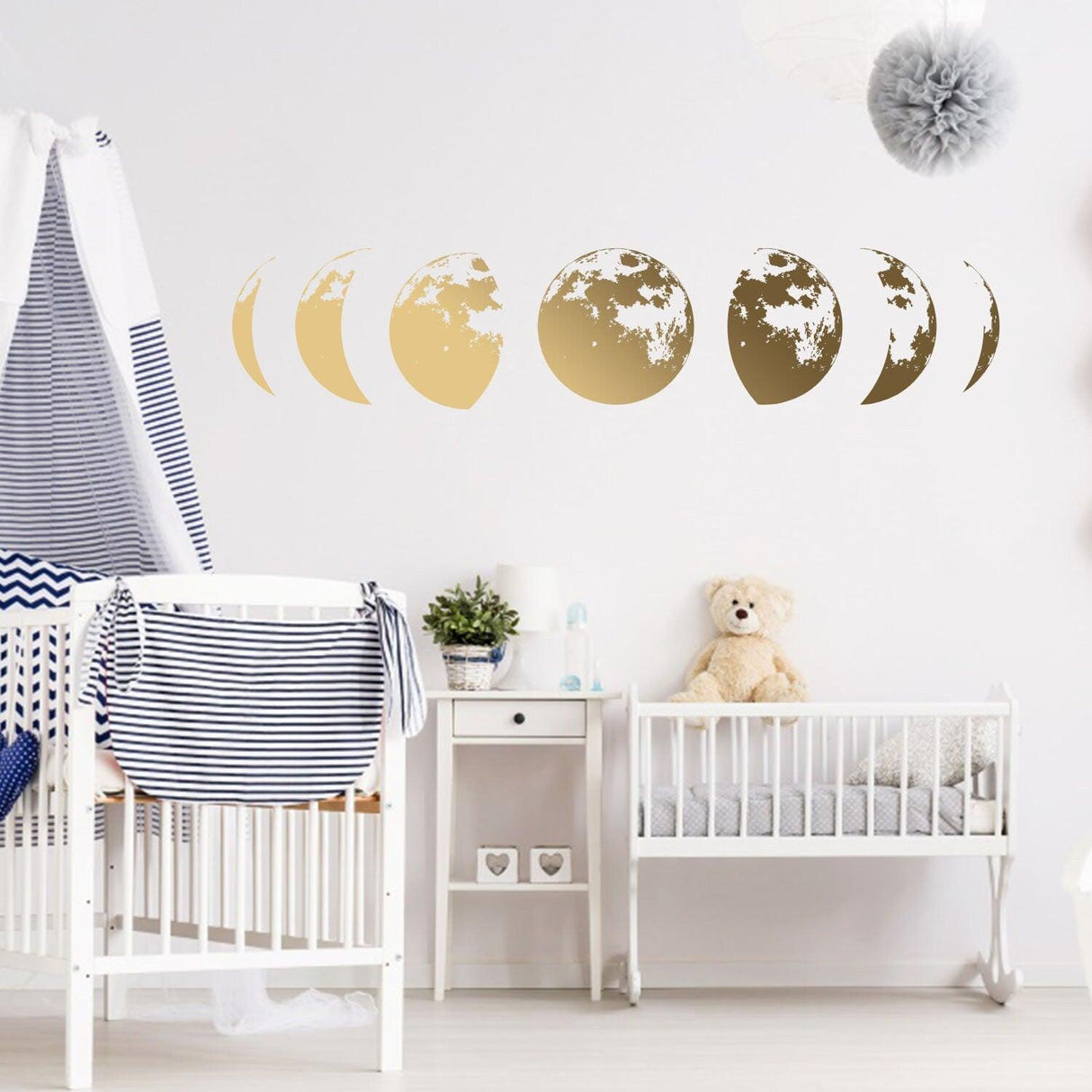Gold moon phases wall decal in a nursery, adding elegance to baby room decor with a cute teddy bear.
