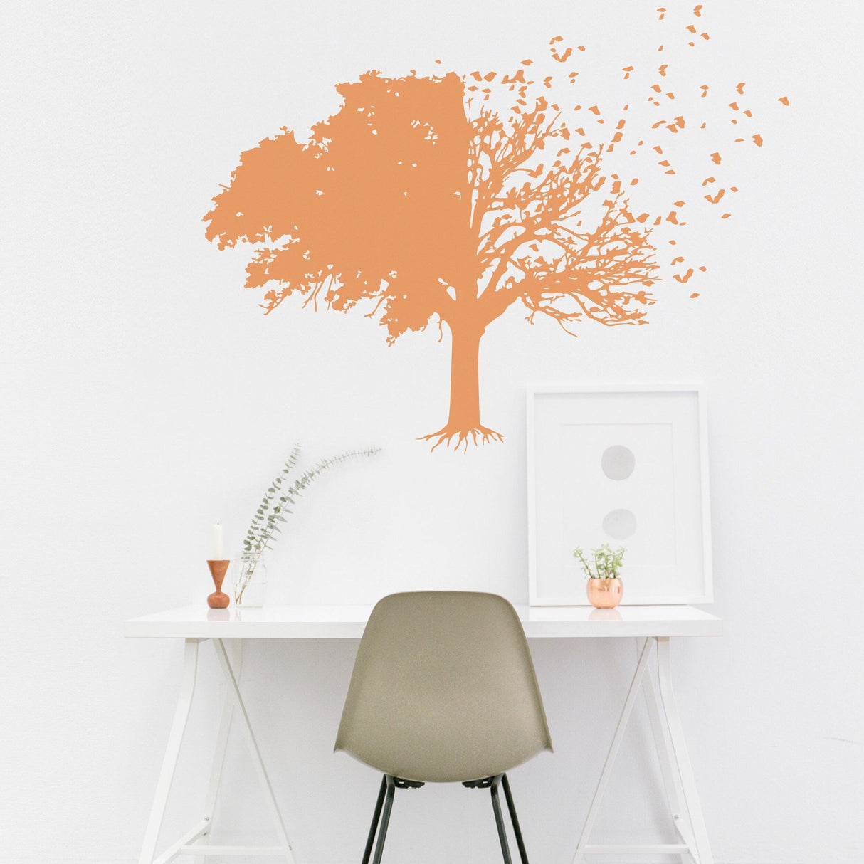 Tree wall decal in orange color with falling leaves, enhancing a minimalist workspace decor.