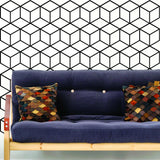 Geometric wall mural decal featuring a hexagon honeycomb design behind a blue couch with decorative pillows.