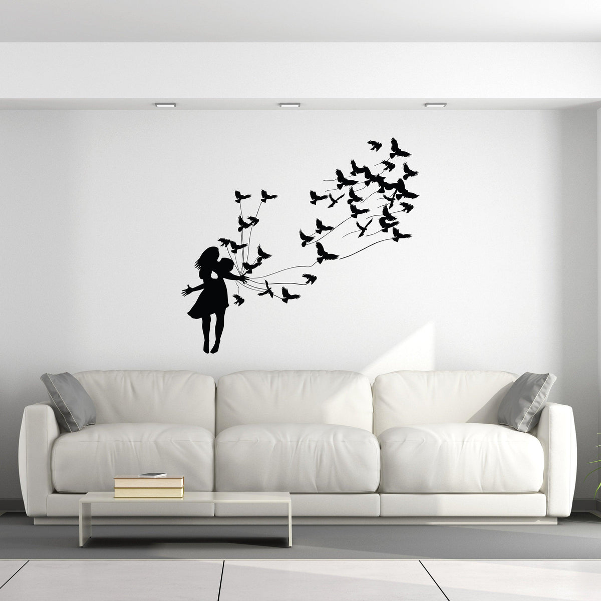 Silhouette wall decal of a girl releasing birds, creating a whimsical and artistic home decor piece.