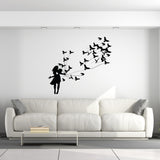 Silhouette wall decal of a girl releasing birds, creating a whimsical and artistic home decor piece.