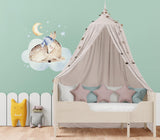 Whimsical baby nursery featuring a wall sticker of a deer on a cloud with stars and a moon, cozy bedding, and playful decor.