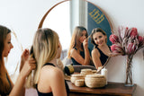 Two women in front of a mirror with a motivational vinyl decal, showcasing self-love and positivity.