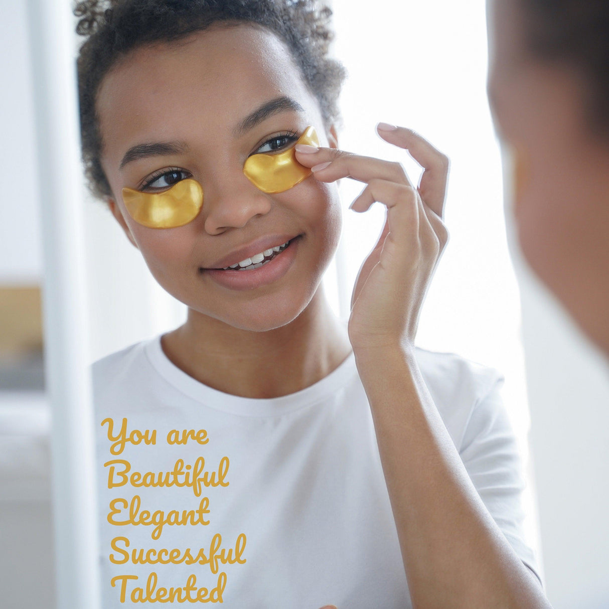 Girl applying gold eye gel patches with motivational affirmations in the mirror, promoting self-love and positivity.