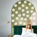 A woman enjoying her bedroom with 24 white daisy wall decals on a stylish green wall.