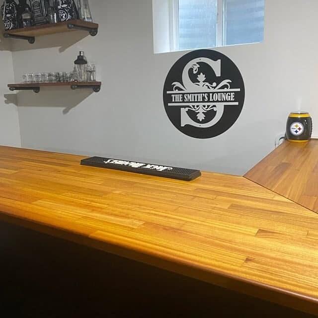 Custom wall art in a home bar showcasing 'The Smith's Lounge' logo and a wood countertop.