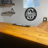 Custom wall art in a home bar showcasing 'The Smith's Lounge' logo and a wood countertop.