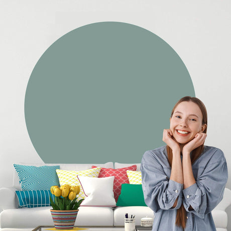 Smiling woman in front of a Scandinavian style circle wall sticker in a cozy living room with colorful cushions.