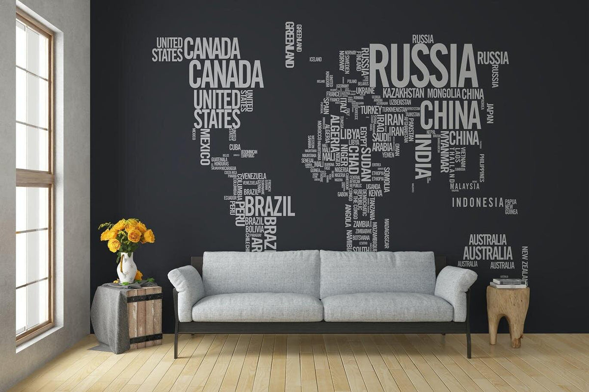 Custom wall art featuring a world map design made of country names on a dark wall above a cozy gray sofa.