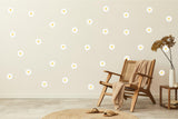 Elegant white daisy wall decals arranged on a light wall beside a cozy chair and natural decor.