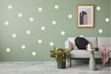 Elegant white daisy wall decals on a green wall, styled with a cozy living room setting and modern decor.