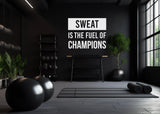 Gym interior with motivational wall decal 'Sweat is the Fuel of Champions' and weights.
