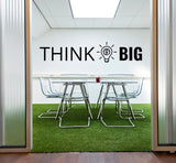Офис с настенной надписью THINK BIG и стеклянным столом.