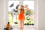 Happy girl in an orange dress posing by Halloween window decals with bats, pumpkins, and ghost decorations.