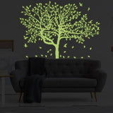 Glow-in-the-dark forest wall decal featuring luminous tree design above a sofa in a cozy living room.